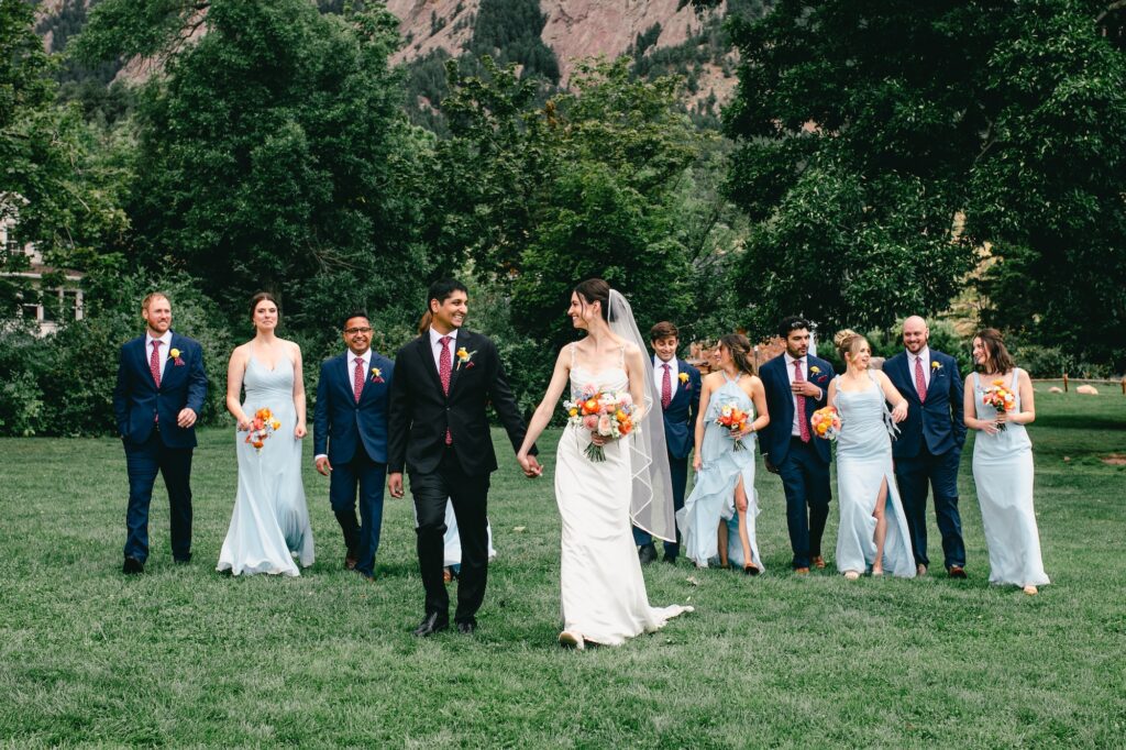 boulder bridal party walks across the green lawn of Chautauqua