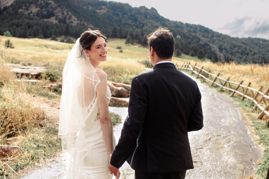 boulder colorado bride and groom walk towards the flatirons during the portrait portion of their wedding timeline