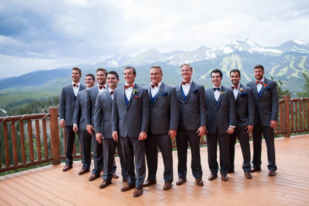 Lodge at Breckenridge groomsmen photo. Groom and groomsmen standing in a line on the deck at The Lodge at Breckenridge with mountain views behind them.