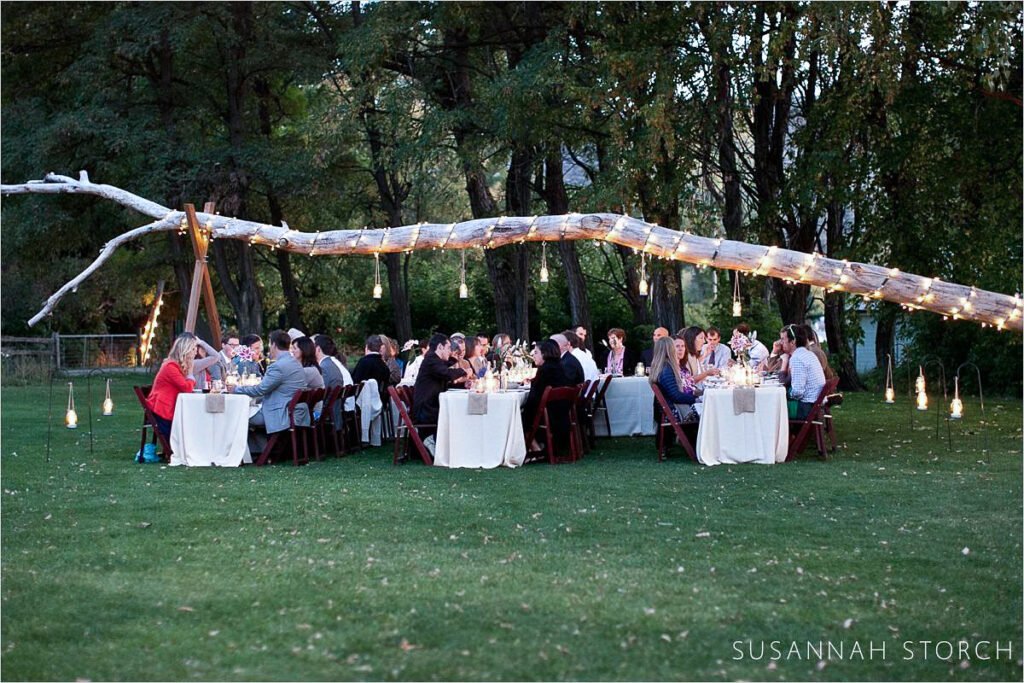 Lyons Farmette wedding meal Lyons Farmette wedding meal with guests eating outdoors under a tree branch wrapped in lights