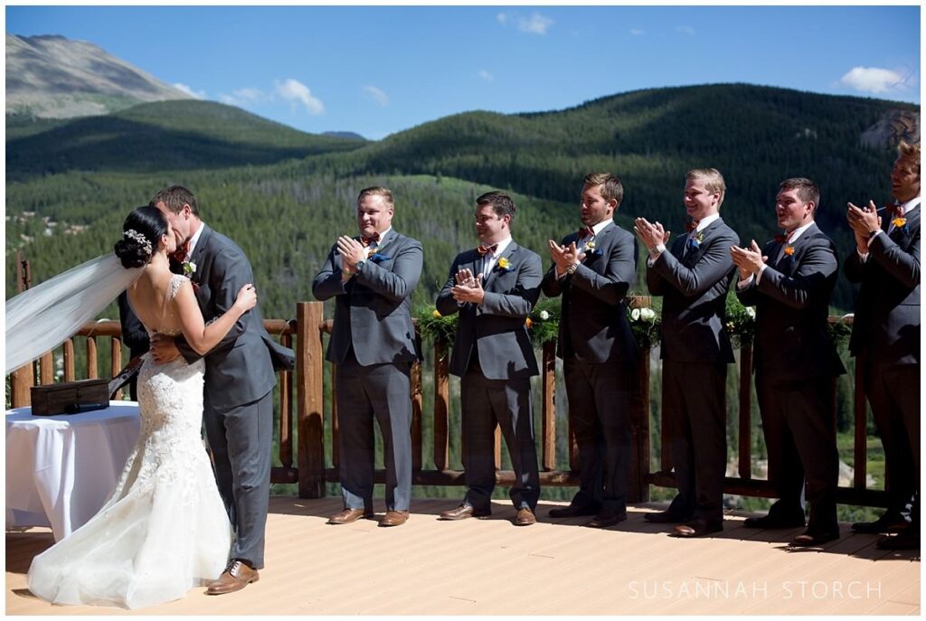 bride and groom kiss at the end of their colorado wedding ceremony on the deck at the lodge at breckenridge
